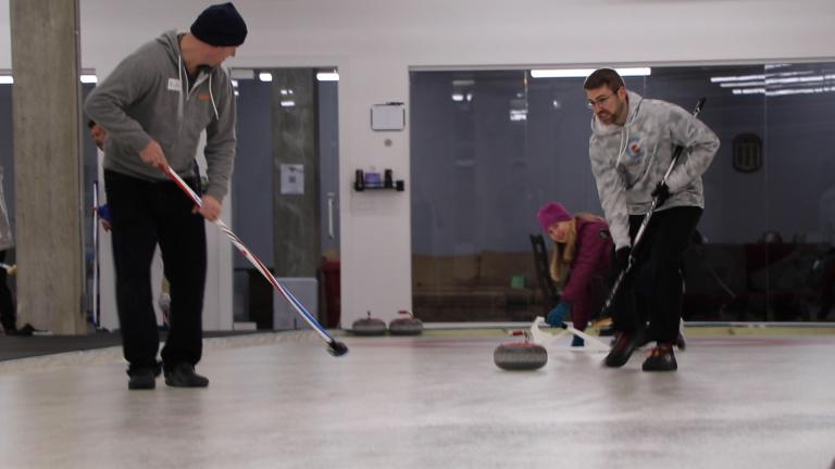 Sweepers follow a curling stone down a sheet of ice at the Windy City Curling Club in Villa Park, Illinois. (Evan Garcia / WTTW News)
