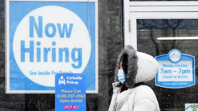 In this Feb. 6, 2021 file photo, a woman walks past a "Now Hiring" sign displayed at a CD One Price Cleaners in Schaumburg, Ill. (AP Photo/Nam Y. Huh, File)
