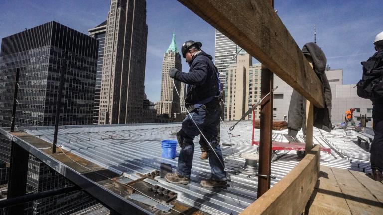 Construction workers install roofing on a high rise in Manhattan’s financial district on Tuesday, April 11, 2023, in New York. (AP Photo / Bebeto Matthews, File)