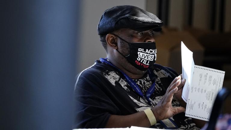 In this Nov. 4, 2020, file photo, an election worker holds a ballot as vote counting in the general election continues at State Farm Arena in Atlanta.  (AP Photo / Brynn Anderson, File)