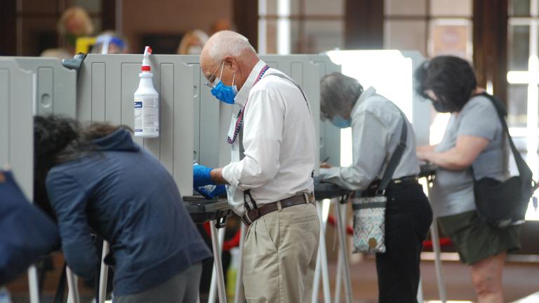 Temporary election worker Joseph Banar, center, disinfects voting stations as a precaution against the coronavirus while a steady stream of voters participates in the first day of balloting in New Mexico, at the Santa Fe Convention Center on Tuesday, Oct. 6, 2020, in Santa Fe, N.M. (AP Photo / Morgan Lee)