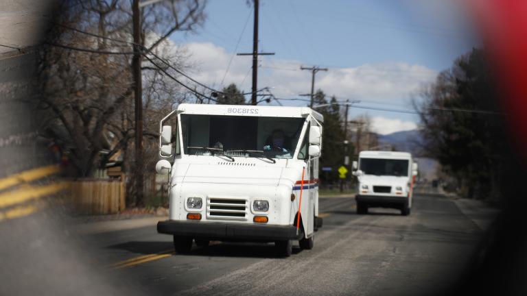 In this March 31, 2020, file photo United States Post Office delivery trucks are reflected in the side mirror of a vehicle as postal delivers set off on their daily rounds in Arvada, Colo. (AP Photo / David Zalubowski, File)