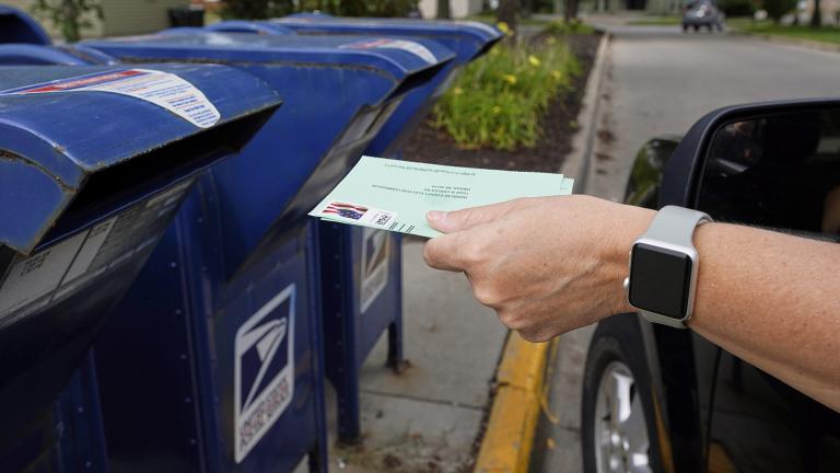 In this Tuesday, Aug. 18, 2020, file photo, a person drops applications for mail-in-ballots into a mail box in Omaha, Neb. (AP Photo / Nati Harnik, File)