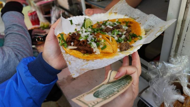 A bicyclist receives food from a street vendor Yulisa Robles, right, at Gage Park during Street Vendor Bike Tour Series, in Chicago, Sunday, Nov. 2, 2025. (AP Photo / Nam Y. Huh)