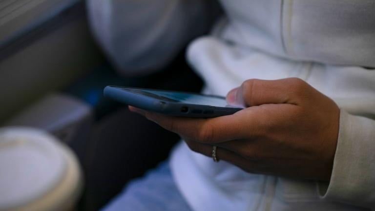 FILE - A woman looks at a hand held device on a train in New Jersey on May 18, 2021. (Jenny Kane / AP Photo, File)