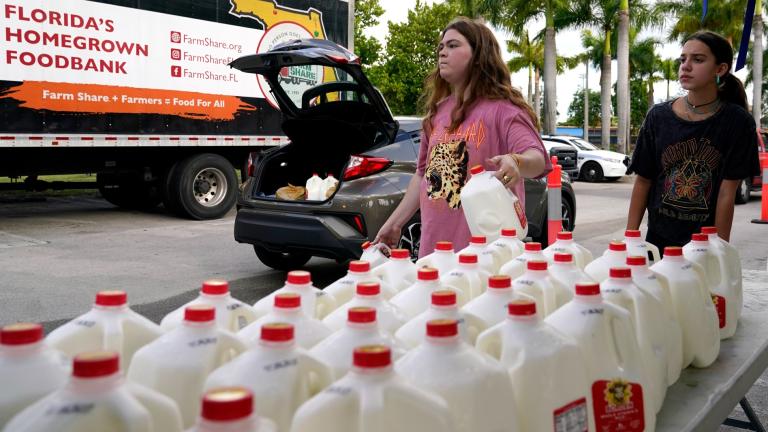Vanessa Correa, left, and Gigi Fiske, right, pass out gallons of milk at a food distribution held by the Farm Share food bank, Wednesday, July 20, 2022, in Miami. (AP Photo / Lynne Sladky)