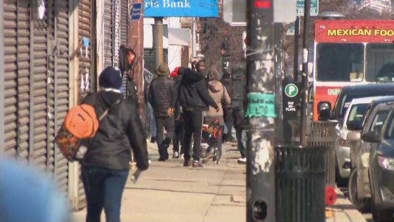 People walk along a busy street in Garfield Park on Wednesday, April 1, 2020. (WTTW News)