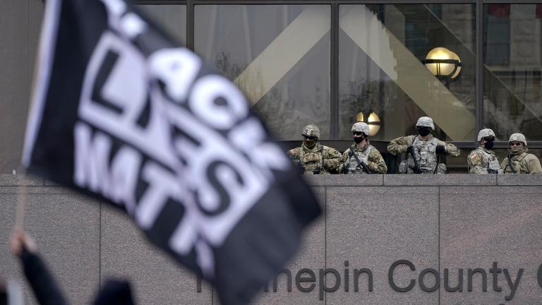 National Guard members are seen as a person flies a Black Lives Matter flag during a rally outside of the Hennepin County Government Center in Minneapolis on Monday, April 19, 2021, after the murder trial against former Minneapolis police Officer Derek Chauvin advanced to jury deliberations. (AP Photo / Julio Cortez)