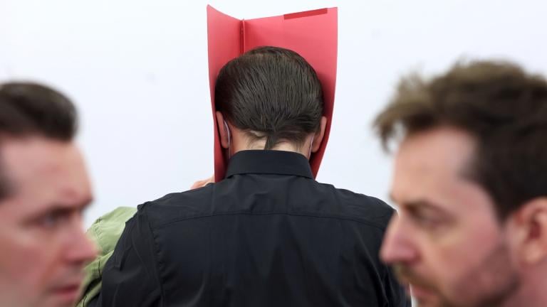 A 31-year-old American man accused of murder, center, stands in the dock between his lawyers Philip M'ller, left, and Alexander Stevens at the regional court in Kempten, Germany, Monday March 11, 2024. (Karl-Josef Hildenbrand / dpa via AP)