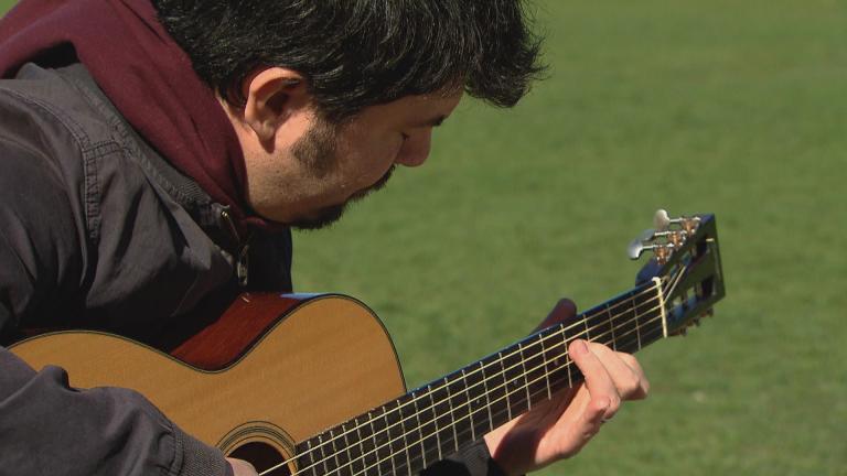 Goran Ivanovic plays guitar at a Chicago park. (WTTW News)