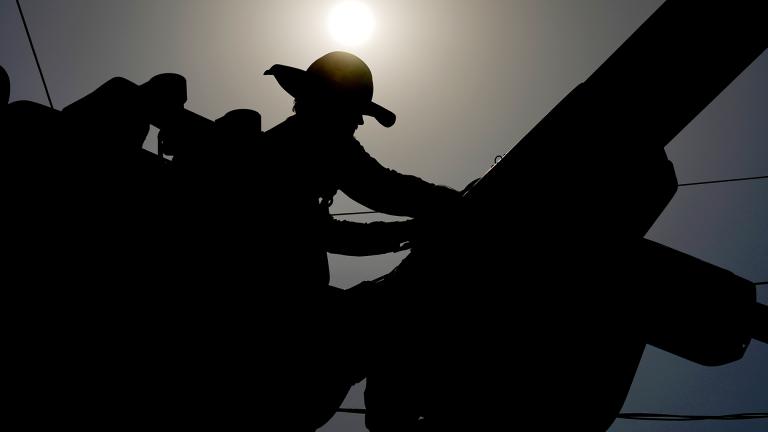 A linesman works on power lines under the morning sun, July 12, 2024, in Phoenix. (AP Photo / Matt York)