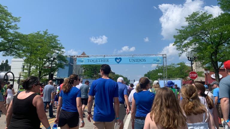 A crowd retraces the Highland Park Fourth of July parade route on July 4, 2023, one year after a mass shooting in the suburb left seven dead. (Eunice Alpasan / WTTW News)