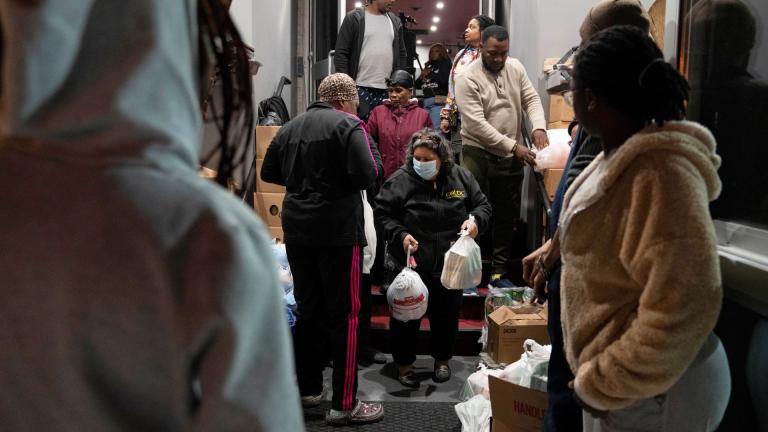 Maria Correa, of Washington, center, who says she is sick with cancer, cannot work, and that things are especially difficult because of the pandemic, accepts a turkey and Thanksgiving trimmings during an annual Thanksgiving food giveaway at The Redeemed Christian Church of God New Wine Assembly, Tuesday, Nov. 22, 2022, in Washington. (AP Photo/Jacquelyn Martin)