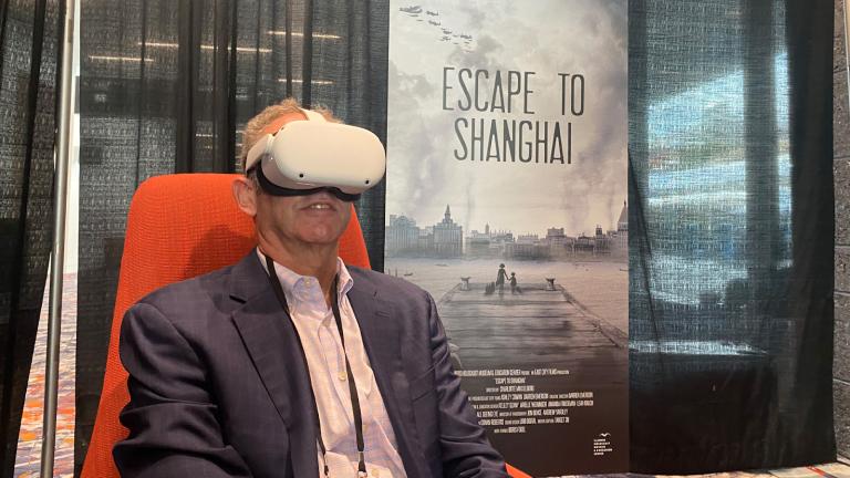 Illinois Holocaust Museum board member Andy Lowenthal demonstrates the virtual reality headset available to convention attendees. (Nick Blumberg / WTTW News)
