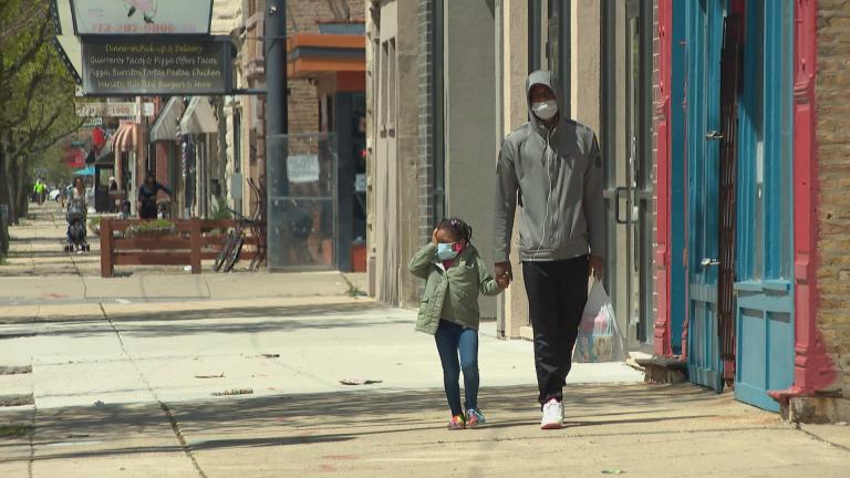 Family members wearing masks walk along the sidewalk in the Humboldt Park neighborhood on Thursday, May 7, 2020. Under Gov. J.B. Pritzker’s stay-at-home order, all residents should wear face masks or coverings when social distancing is not possible. (WTTW News)