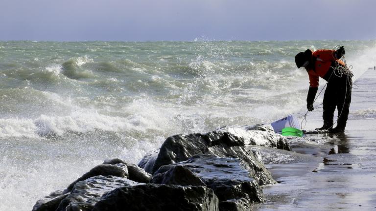 Rae-Ann Eifert, a lake monitor for the Wisconsin Department of Natural Resources, braved sub-freezing temperatures to gather buckets of water for testing off a Lake Michigan breakwater in Racine, Wis., on Feb. 28, 2024, as part of an effort across the Great Lakes to understand the effects of an iceless winter. (AP Photo/Teresa Crawford)