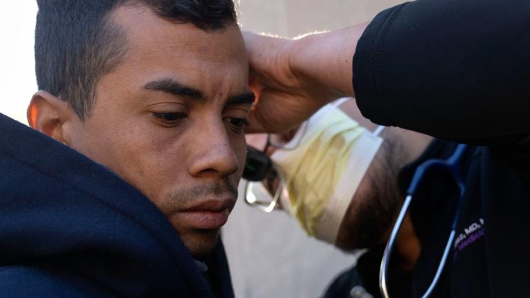 Dr. Ray Mendez, right, examines Moises Abraham Hidalgo Sarmiento, 30, of Peru outside of the 1st District police station where migrants are camped, Saturday, Oct. 7, 2023, in Chicago. (Erin Hooley / AP Photo)