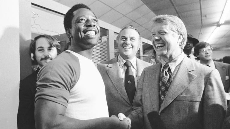 FILE - Georgia Gov. Jimmy Carter, right, and Delaware Gov. Sherman Tribbitt say hello to Atlanta Braves Hank Aaron, left, following a rain canceled game with the Los Angeles Dodgers in Atlanta, Ga., Sept. 27, 1973. (AP Photo, File)