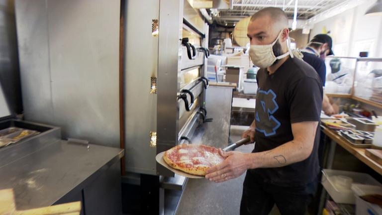 Pete Ternes, owner of the brewpub Bungalow by Middle Brow, takes a pizza out of the Logan Square restaurant’s oven on April 30, 2021. Bungalow by Middle Brow is one of several vendors participating in this year’s Logan Square Farmers Market. (WTTW News)