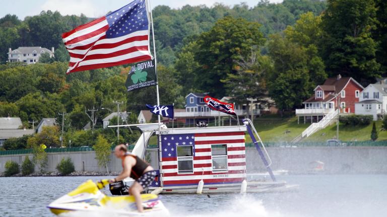 A jet skier passes a patriotic shanty-boat owned by AJ Crea on Pontoosuc Lake on Labor Day in Pittsfield, Mass., Monday, Sept. 7, 2020. (Ben Garver / The Berkshire Eagle via AP)