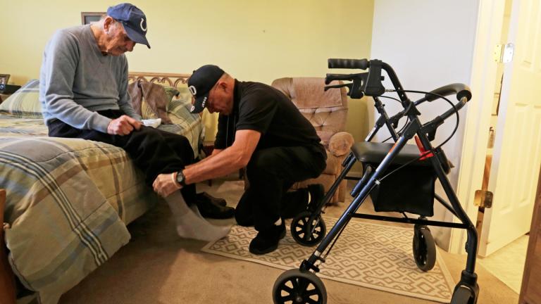 Caregiver Warren Manchess helping Paul Gregoline with his shoes and socks, in Noblesville, Ind., Nov. 27, 2013. (AP Photo / Darron Cummings, File)