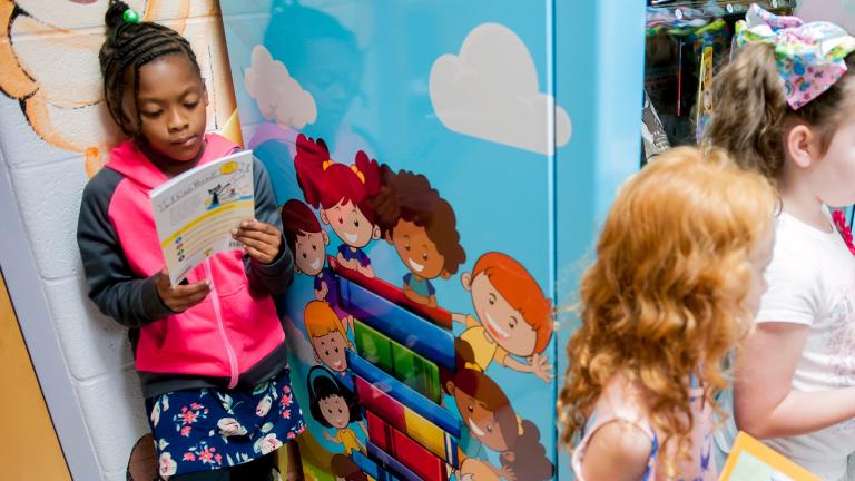 Janaya Sells, 7, reads a token-bought book on Sept. 26, 2019, during a ribbon cutting for an Inchy the Worm book vending machine at R.E. Stevenson Elementary School in Russellville, Ky. (Bac Totrong/Daily News via AP, File)