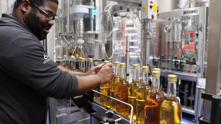 CH Distillery employee Nick White sends several bottles of Malort down the bottling production line. (Evan Garcia / WTTW News)