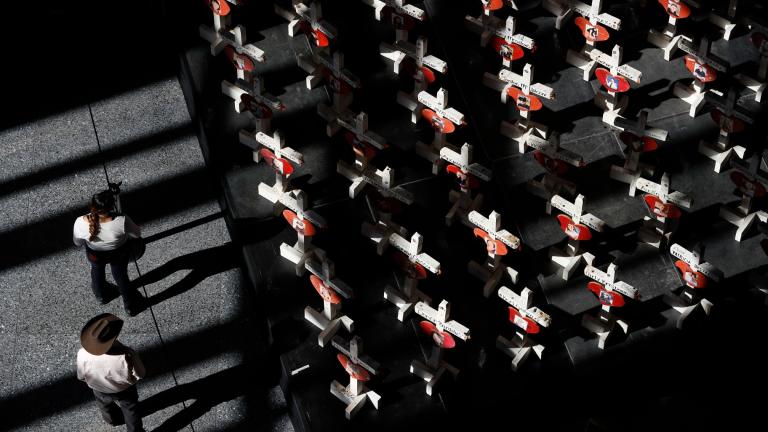 In this Sept. 25, 2018, photo, people look at a display of wooden crosses and a Star of David on display at the Clark County Government Center in Las Vegas. (AP Photo / John Locher, File)