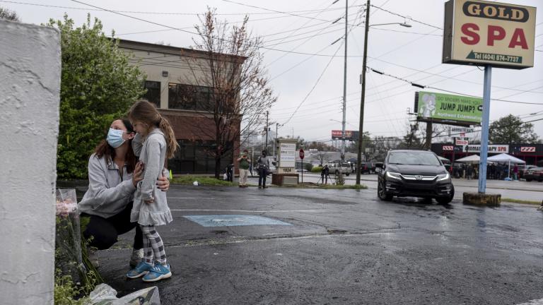 Mallory Rahman and her daughter Zara Rahman, 4, who live nearby, pause after bringing flowers to the Gold Spa massage parlor in Atlanta, Wednesday afternoon, March 17, 2021, the day after eight people were killed at three massage spas in the Atlanta area. (AP Photo/Ben Gray)