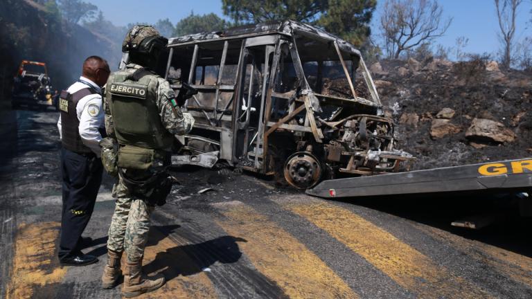 A soldier stands guard by a charred vehicle that was set on fire in Cointzio, Mexico, Sunday, Feb. 22, 2026, amid reports the Mexican Army killed Jalisco New Generation Cartel leader Nemesio Oseguera, known as "El Mencho." (AP Photo / Armando Solis)