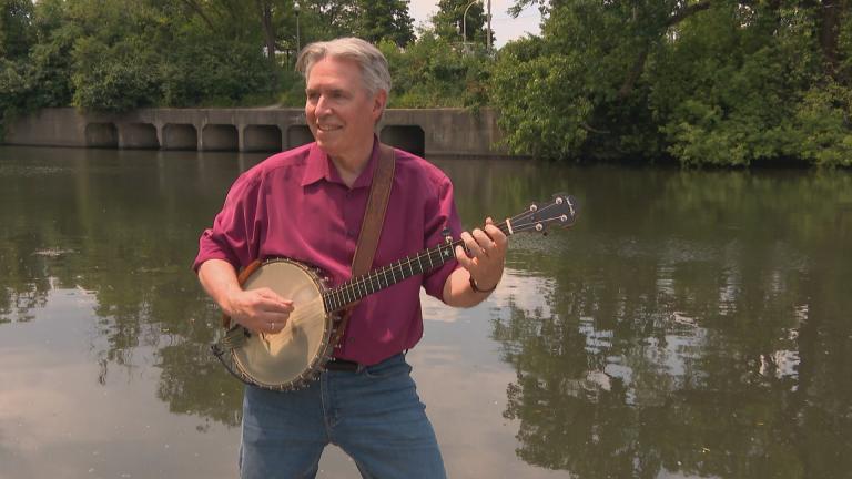 Michael Miles plays his banjo on the banks of the Chicago River. (WTTW News)