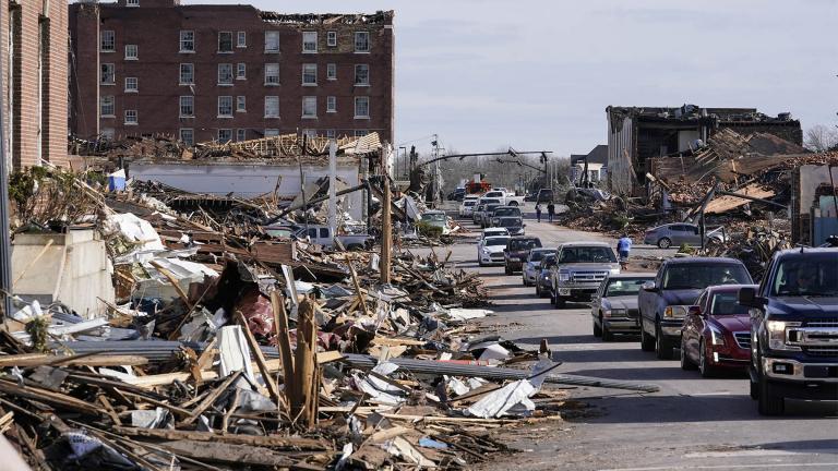 Automobiles line up near debris from tornado damage in Mayfield, Ky., on Saturday, Dec. 11, 2021. Tornadoes and severe weather caused catastrophic damage across multiple states Friday, killing multiple people overnight. (AP Photo / Mark Humphrey)