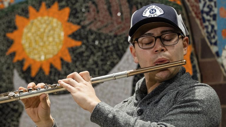 Donald Rabin plays the flute after Detective George Hilbring retrieved and returned it to him during a news conference at the 14th District Police Station on Thursday, Feb. 4, 2021. (Pat Nabong / Chicago Sun-Times via AP)