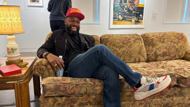 Chicago-born artist Nathaniel Mary Quinn sits in his recreated childhood living room on May 20, 2026, at the National Public Housing Museum as part of his exhibit, “Nathaniel Mary Quinn: A Love Letter to My Mother.” The exhibit runs until Aug. 23. (Eunice Alpasan / WTTW News)
