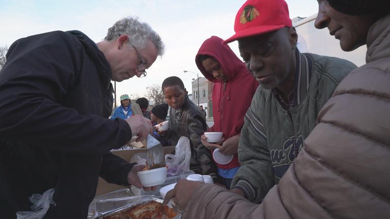 A Night Ministry volunteer serves lasagna to members of the Back of the Yards community.