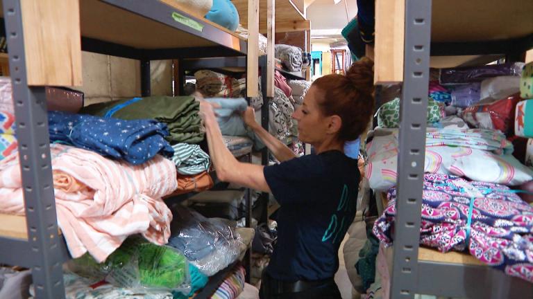 A Digs With Dignity worker sorts through items at the nonprofit’s warehouse on June 30, 2025. The organization, which helps people exiting homelessness furnish and decorate their new residence, is part of the new networking group Chicago Nonprofit Connect. (WTTW News)
