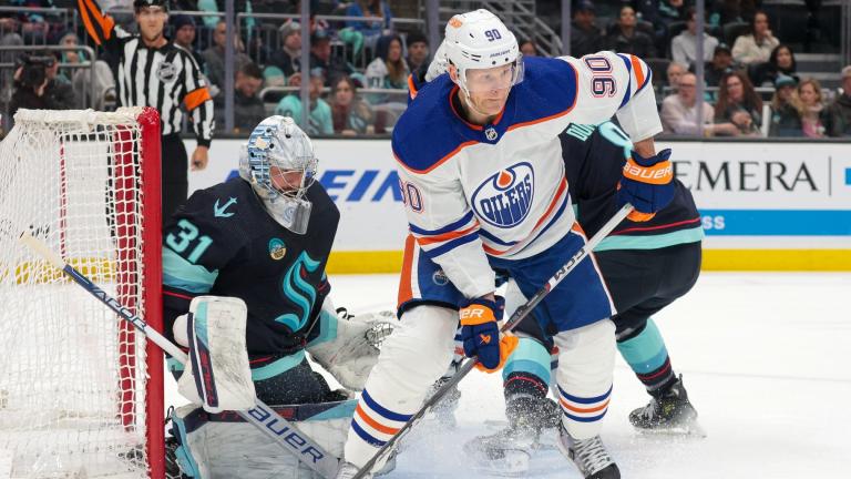 Edmonton Oilers right wing Corey Perry (90) moves the puck as Seattle Kraken goaltender Philipp Grubauer (31) and defenseman Brian Dumoulin (8) defend during the second period of an NHL hockey game Saturday, March 2, 2024, in Seattle. (AP Photo / Jason Redmond)