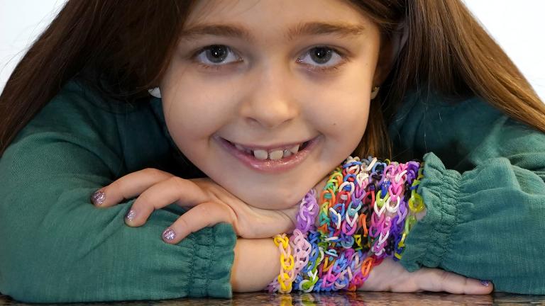 Hayley Orlinsky poses for a portrait Wednesday, Dec. 2, 2020, with several colorful rubber band bracelets she makes in her Chicago home. (AP Photo / Charles Rex Arbogast)
