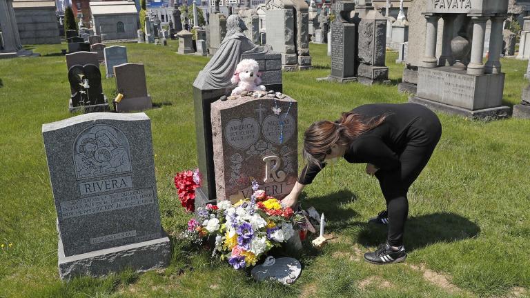 In this Sunday, May 10, 2020 file photo, Sharon Rivera adjusts flowers and other items left at the grave of her daughter, Victoria, at Calvary Cemetery in New York, on Mother’s Day. (AP Photo / Kathy Willens, File)