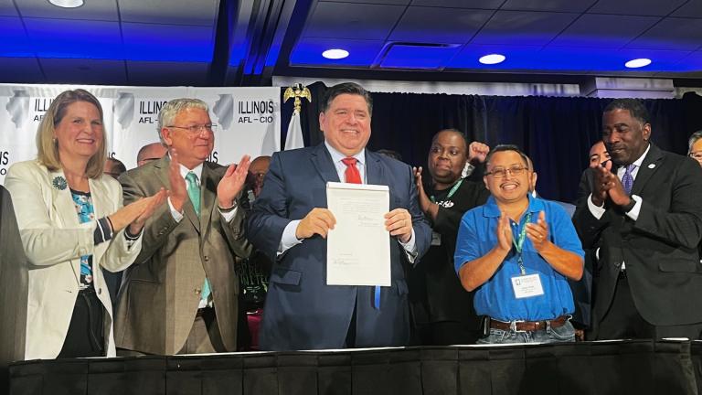 After signing legislation aimed at curtailing the practice of what sponsors dubbed “captive audience meetings,” in which workers are required to listen to their employer’s religious or political views, Gov. J.B. Pritzker poses with the bill at the Illinois AFL-CIO's biennial convention in Rosemont on Wednesday, July 31, 2024. Pritzker is flanked by AFL-CIO's national president, Liz Shuler, and the state organization’s president, Tim Drea (left), and state Rep. Marcus Evans, D-Chicago (right), along with oth