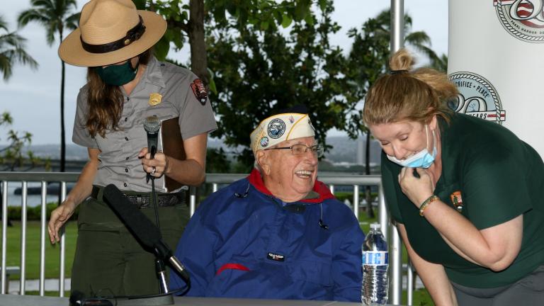 Pearl Harbor survivor Herb Elfring, center, speaks with National Park Service workers in Pearl Harbor, Hawaii on Sunday, Dec. 5, 2021. (AP Photo/Audrey McAvoy)