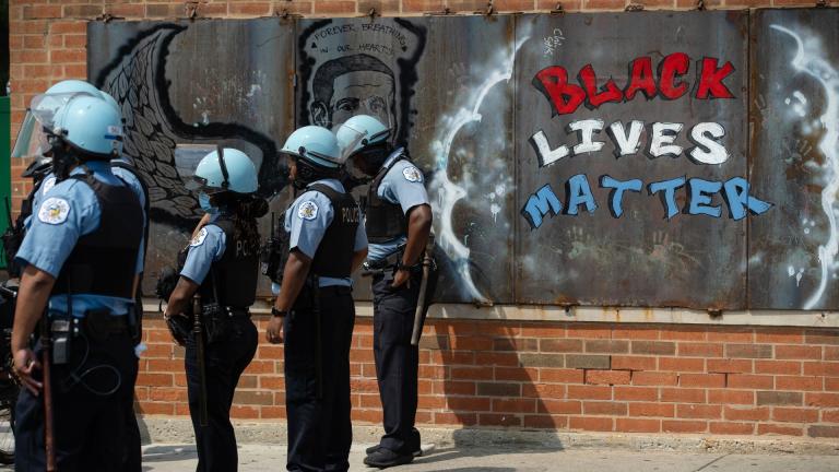 In this Aug. 15, 2020, file photo, police officers stand beside a mural for George Floyd in the Chicago neighborhood of Bronzeville during an anti-police brutality protest. (Pat Nabong / Chicago Sun-Times via AP, File)