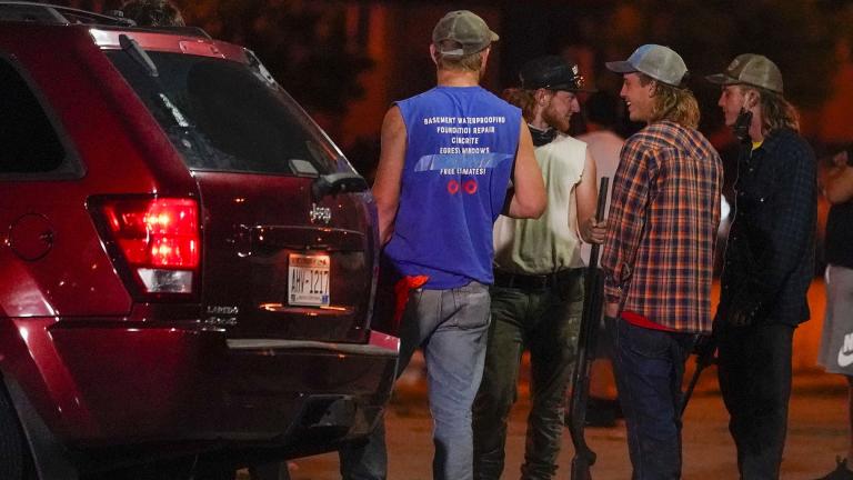 A group holds rifles as they watch protesters on the street Tuesday, Aug. 25, 2020, in Kenosha, Wis. Protests continued following the police shooting of Jacob Blake two days earlier. (AP Photo / Morry Gash)