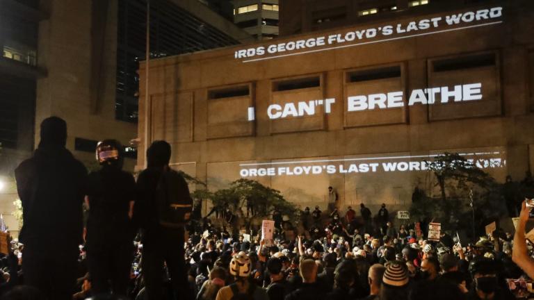 In this Saturday, July 25, 2020, file photo, the words "I can't breathe" are flashed on a wall during a Black Lives Matter protest in Portland, Ore. (AP Photo/Marcio Jose Sanchez, File)