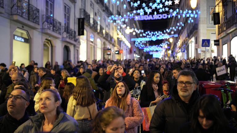 People look up at Christmas lights as crowds stroll around downtown Lisbon's Chiado neighborhood, Saturday evening, Dec. 23, 2023. (AP Photo / Armando Franca)