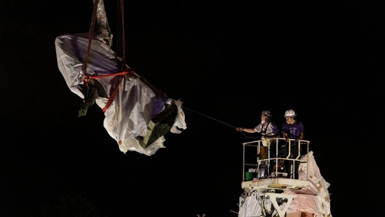 City municipal crews help guide the Christopher Columbus statue in Grant Park as it is removed by a crane, Friday, July 24, 2020, in Chicago. A statue of Christopher Columbus that drew chaotic protests in Chicago was taken down early Friday amid a plan by President Donald Trump to dispatch federal agents to the city. (Tyler LaRiviere / Chicago Sun-Times via AP)