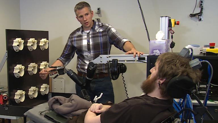 Rob Gaunt from the University of Pittsburgh prepares Nathan Copeland, who was paralyzed in 2004, for a brain computer interface sensory test using a robotic arm. (UPMC / Pitt Health Sciences Media Relations)