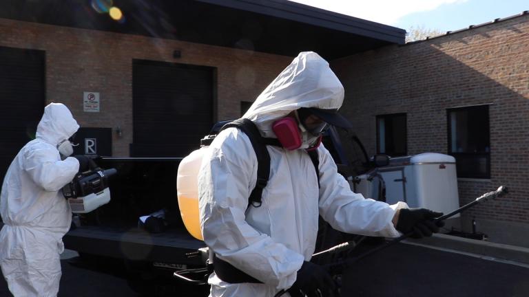 Rozalado Services managing partner Tony Pedroza, left, and director of operations Dominic Amoroso test out the cleaning company’s disinfectant equipment outside its office. (Evan Garcia / WTTW News) 