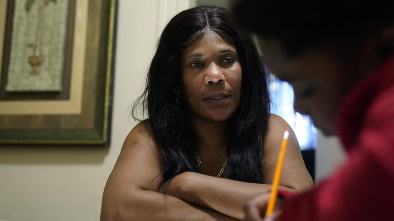 Evena Joseph, left, sits with her son J. Ryan Mathurin, 9, as he does his homework, Thursday, Dec. 22, 2022, at their home, in Boston. (AP Photo/Steven Senne)