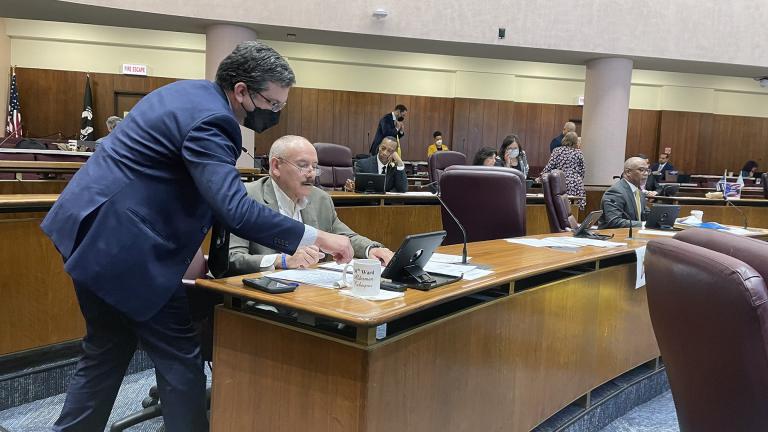 Ald. Scott Waguespack (32nd Ward), left, helps Ald. Ariel Reboras (30th Ward) figure out the electronic voting system. (Heather Cherone / WTTW News)